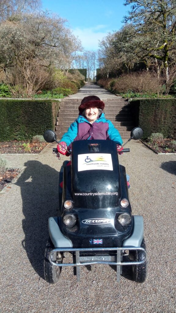 Liz, Countryside Mobility member drives  a Tramper along a historic estate garden