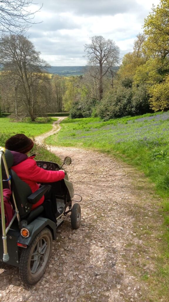 Liz, Countryside Mobility member drives  a Tramper down a windy countryside stoney pathway